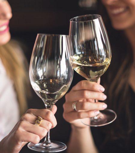 Women toasting with glasses of white wine.