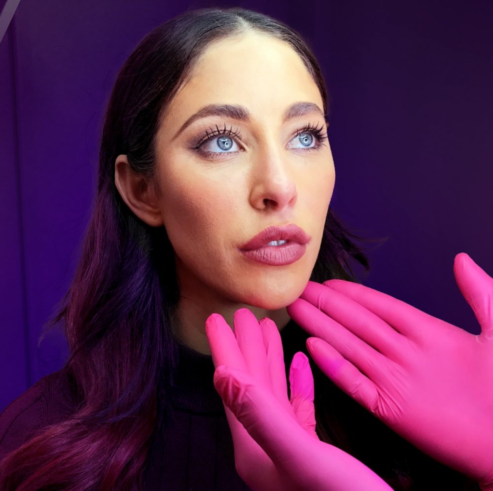 Hands with surgical gloves under a person's chin, tilting the head upwards